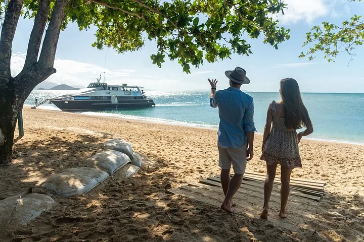 A couple on a sandy beach looking at a boat arriving